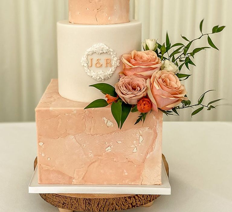 Three tiered wedding cake with marble effect, personalised initials and pink rose decorations 