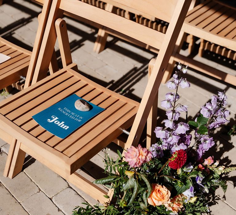 Colourful wedding stationery reserved seat signs on wooden chairs for wedding 