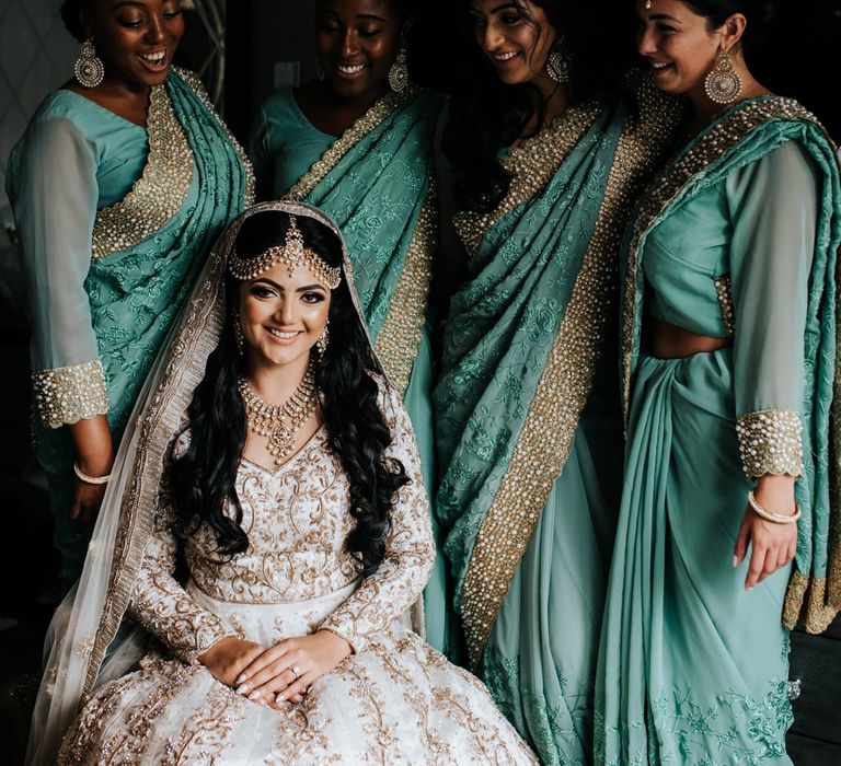 Bridal party on wedding morning in ivory and gold dress gown and green and gold sari's