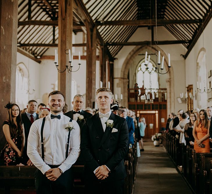 Groom at the altar in navy suit and bow tie