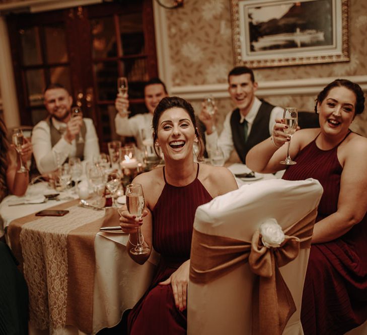 Wedding party raising a toast at winter wedding with burgundy bridesmaid dresses 