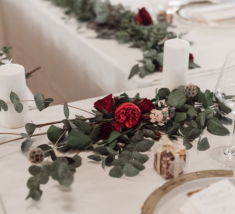 Table decoration with foliage, pilar candles and red roses