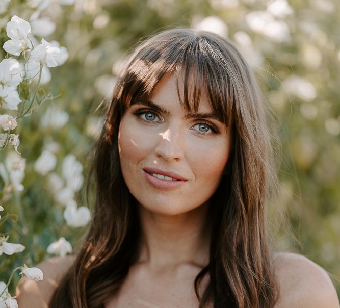 Bridesmaid with long brown hair and fringe in a strapless white midi dress 