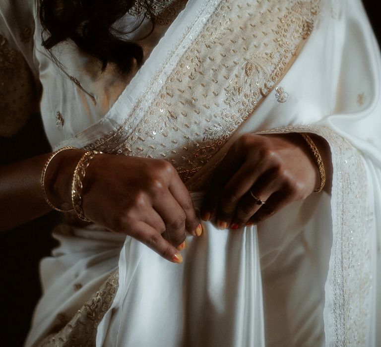 Bride in a white sari with embroidery detail and orange manicured nails 