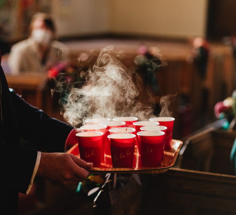 Wedding guest hands out warm drinks in red cups