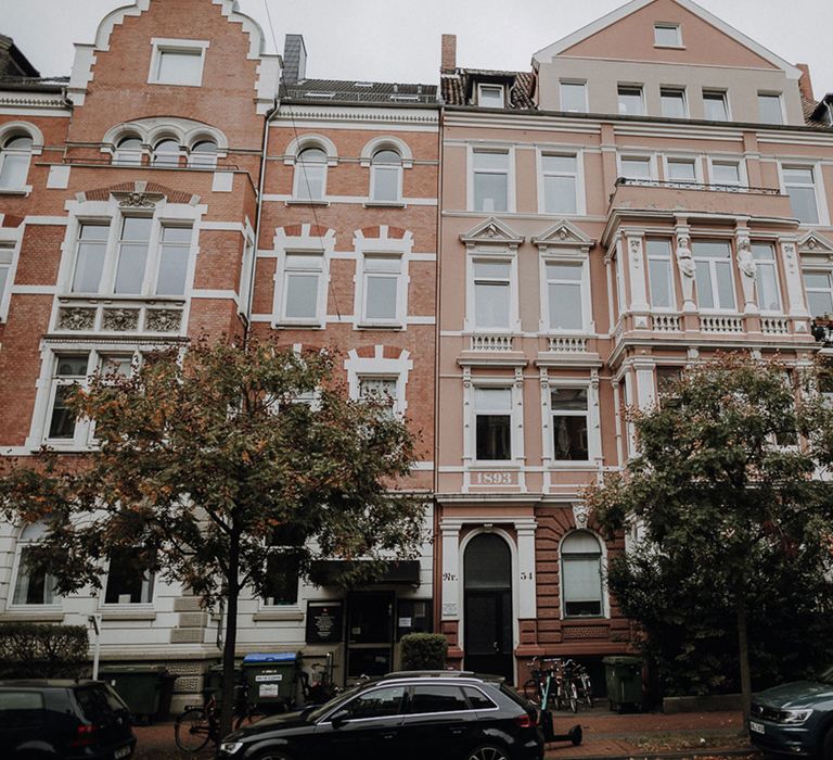 Historic peach coloured five storey house in tree lined street in Germany 