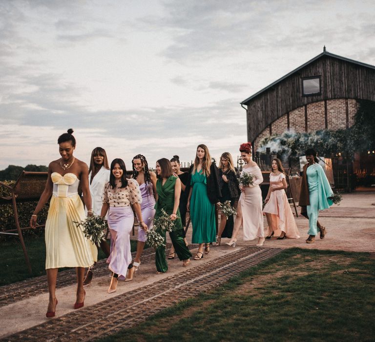 Bridesmaids in different coloured outfits at outdoor wedding ceremony 