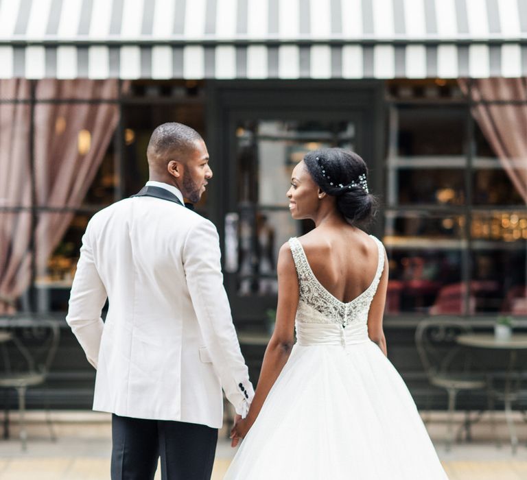 Bride & groom stand holding hands with their backs to the camera