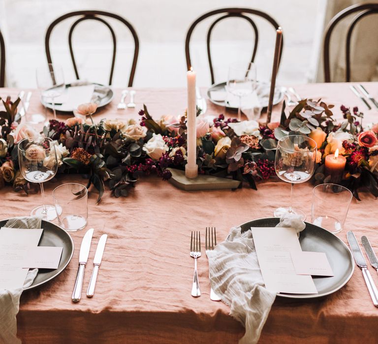 Elegant place settings with black tableware, natural linens and centrepiece flowers 