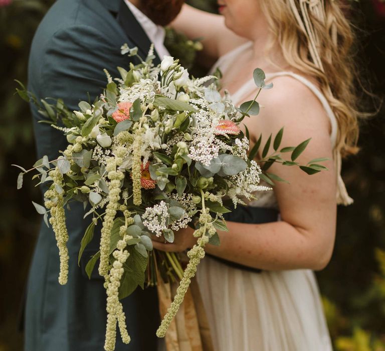 Brie carries white floral bouquet with green foliage