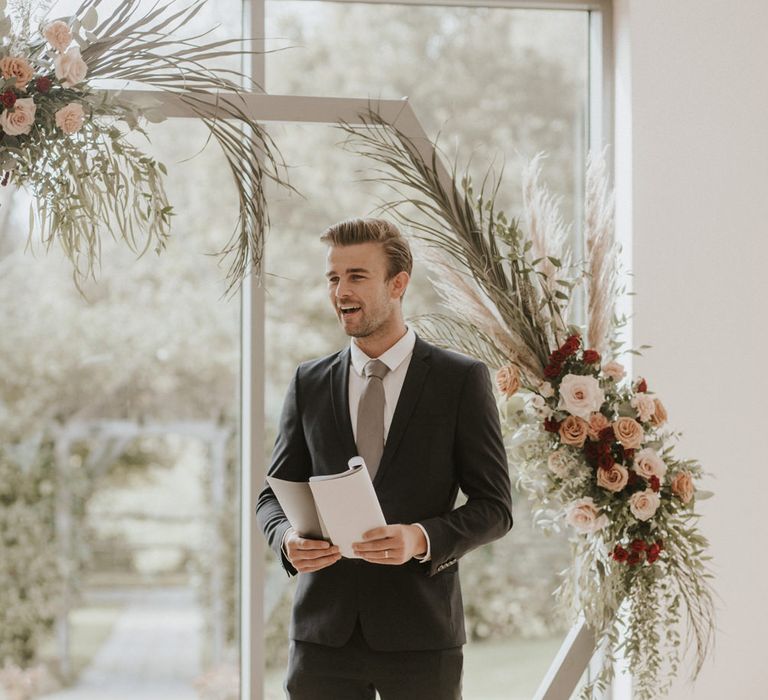 Celebrant standing at the geometric altar with a booklet 