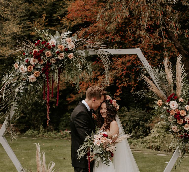 Bride and groom portrait by Nataly J Photography with couple standing in front of a wooden frame 