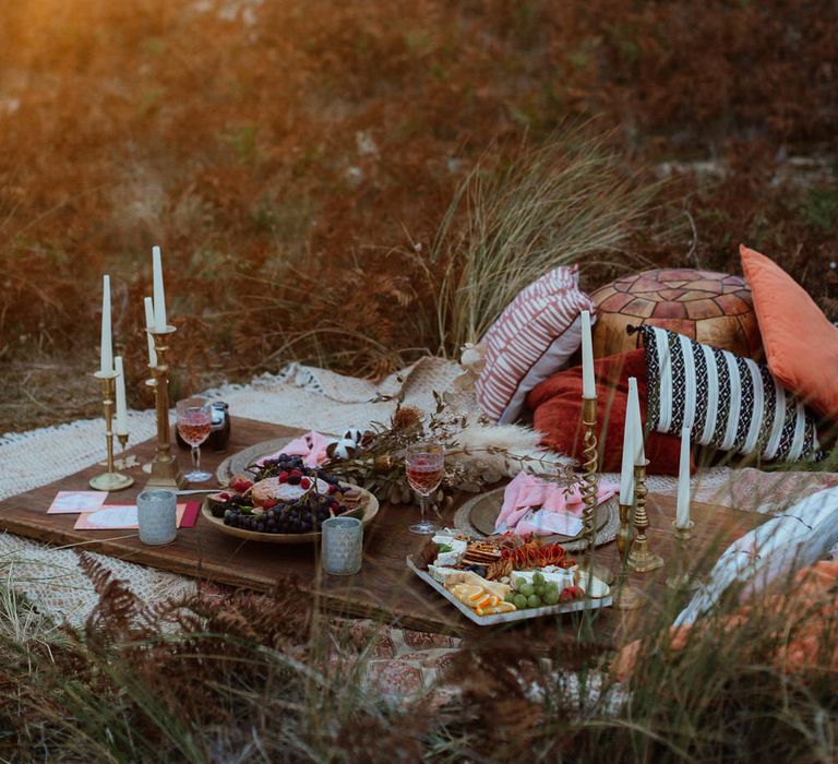 Boho beach picnic set up at sunset with tapered candles