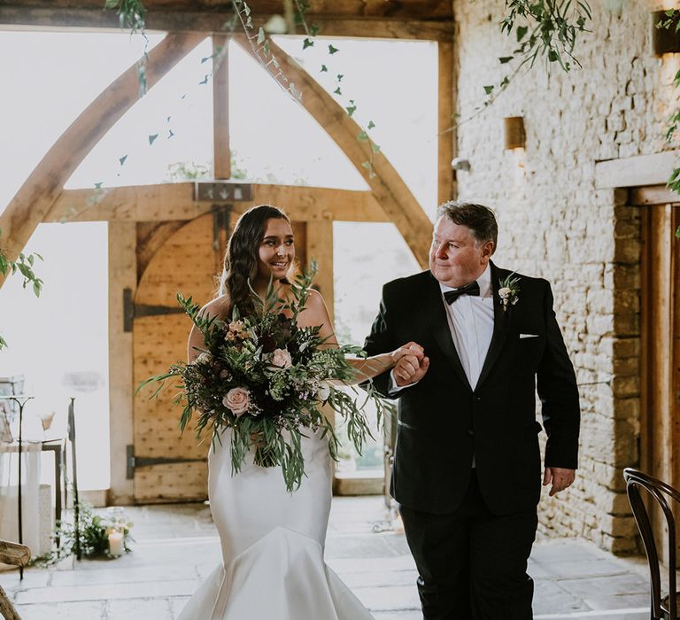 Wedding ceremony bridal entrance with Father of the bride in a tuxedo and the bride in a strapless mermaid wedding dress