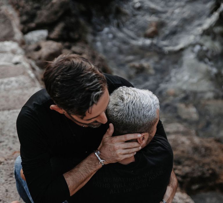 Groom sits on the lap of his boyfriend as they kiss