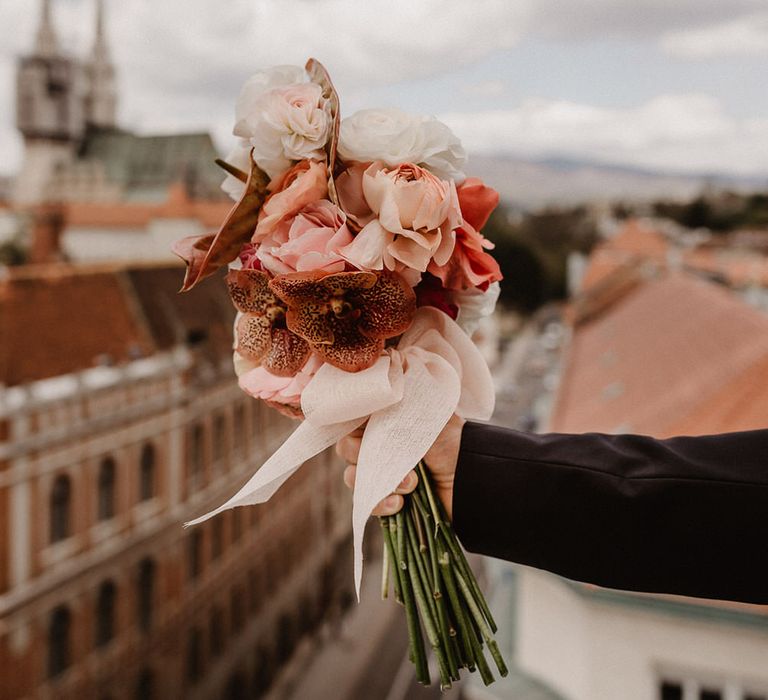 Peach wedding flowers bouquet made of pink, peach and burgundy ranunculi, garden roses and orchids