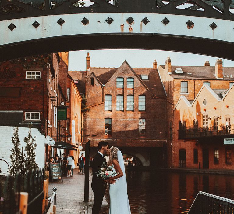 Black tie wedding with bride and groom kissing by the canal in Birmingham