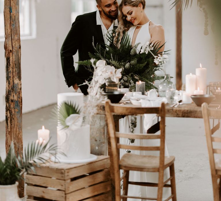 Bride and groom at tropical theme wedding holding a large green bouquet