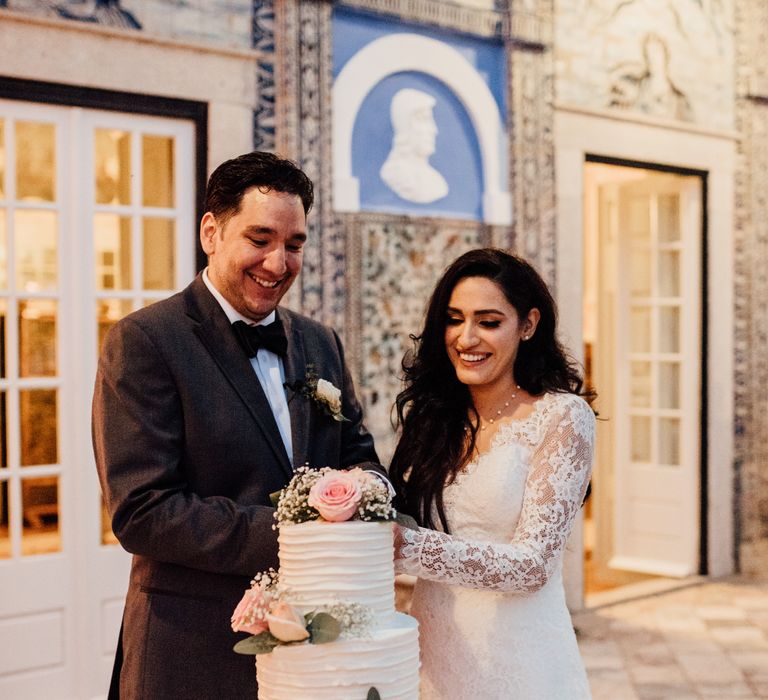 Bride & groom cut wedding cake as bride wears white bridal gown from Pronovias 