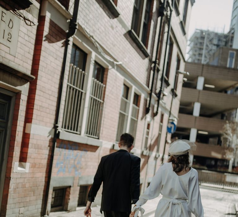 Stylish city wedding with bride in a short wedding dress with long sweeping back bow. 