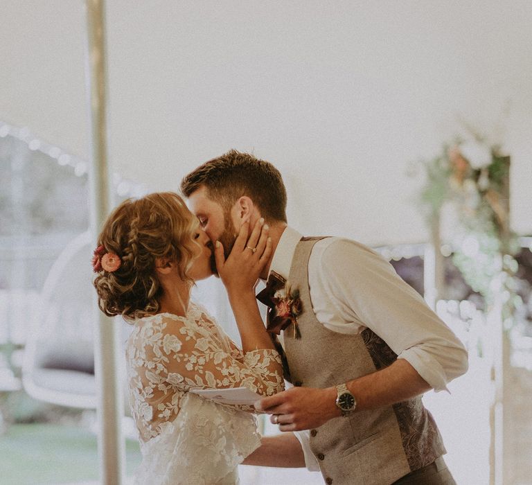 Bride in white Rime Arodaky wedding dress and mesh floral embroidered top kisses groom in waistcoat and white shirt after speech during wedding breakfast