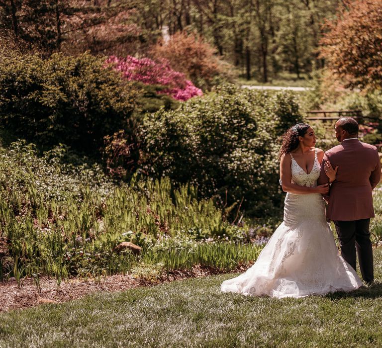 Bride & groom stand within beautiful green gardens for couples portraits after wedding ceremony