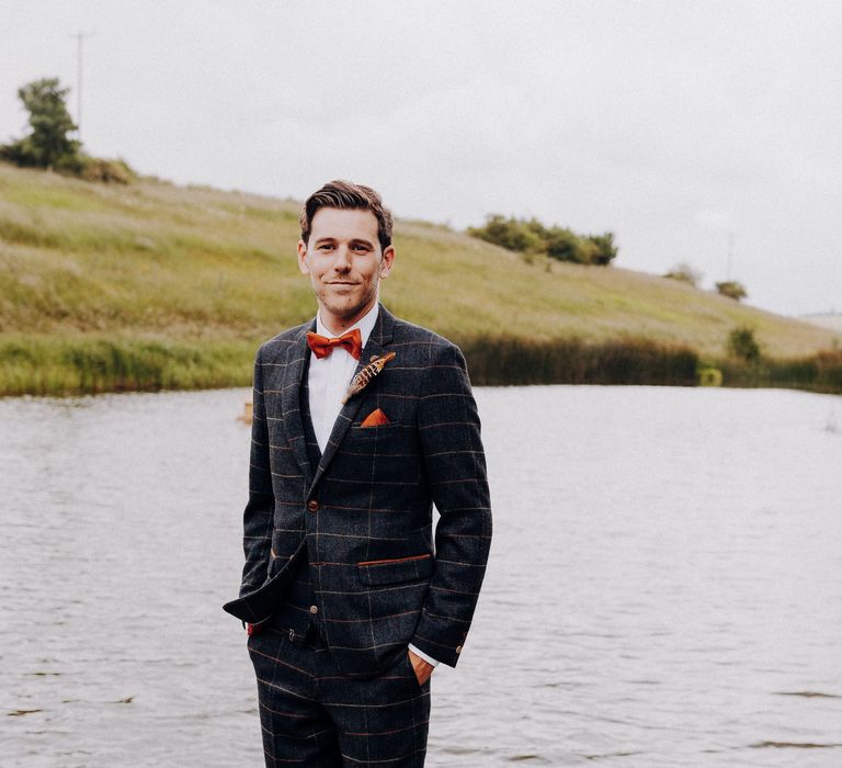 Groom wears Marc Darcy suit complete with orange detailing and pocket square, with feather buttonhole