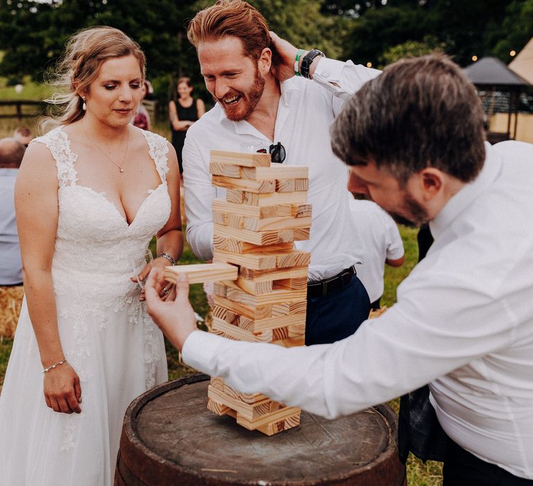 Bride plays jenga outside with friends on her wedding day