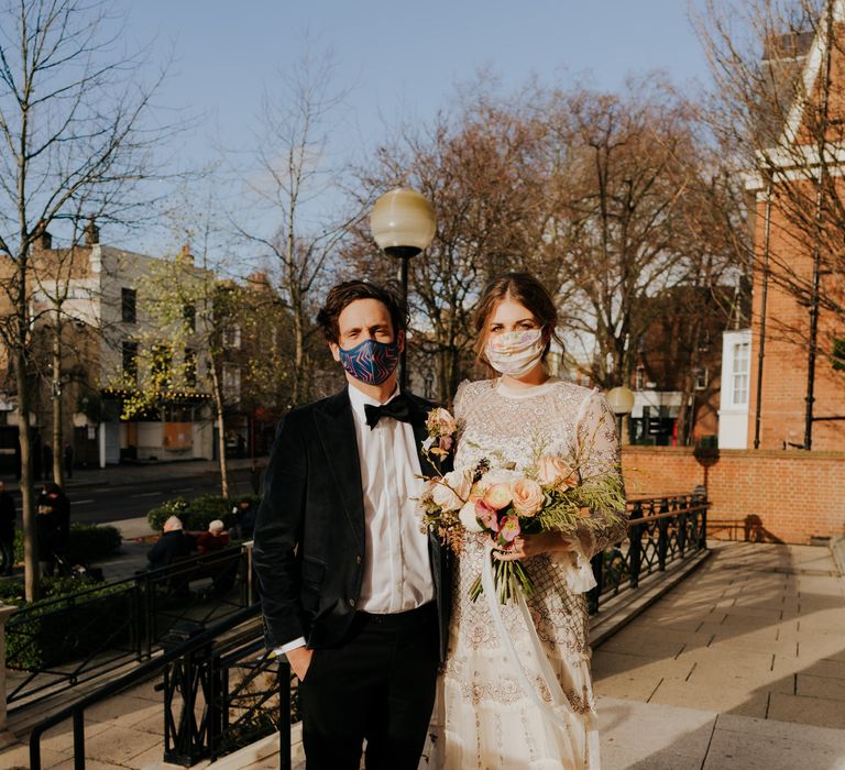 Bride & groom stand outdoors whilst the sun shines for December wedding