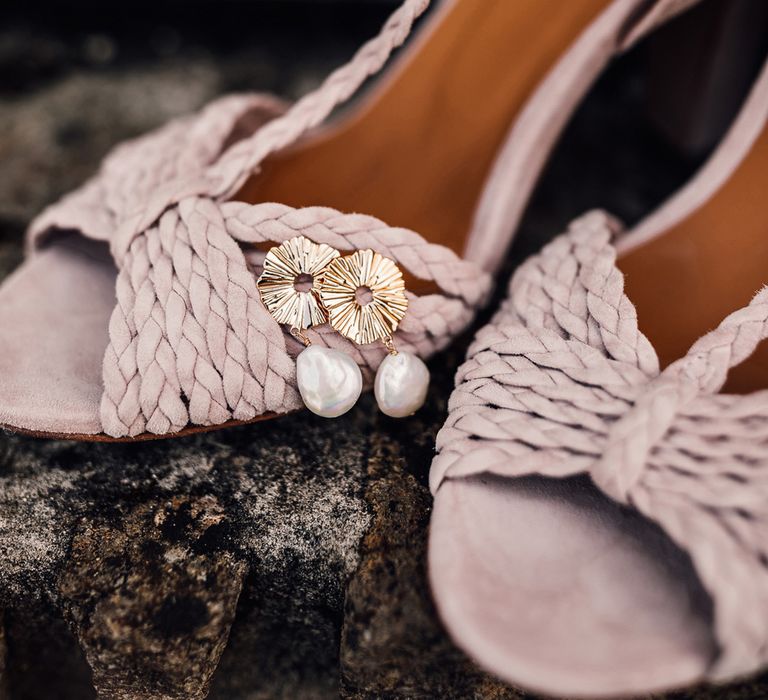 Pink braided sandal heels with gold and pearl earrings on stone step at summer wedding in Dorset