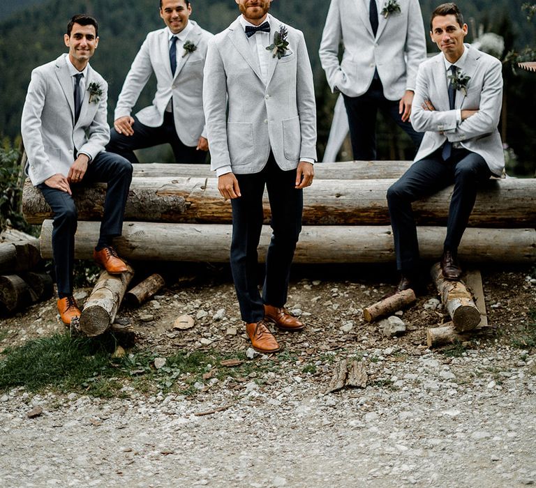 Stylish groomsmen in navy chinos with pale grey blazers at a Swiss Alps outdoor wedding 