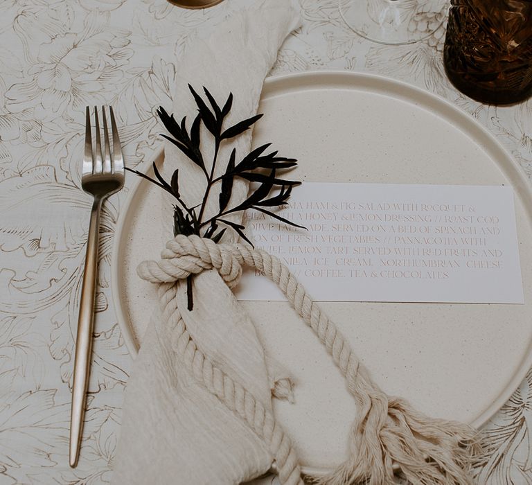 Minimalist wedding place setting with gold cutlery and rope decor 