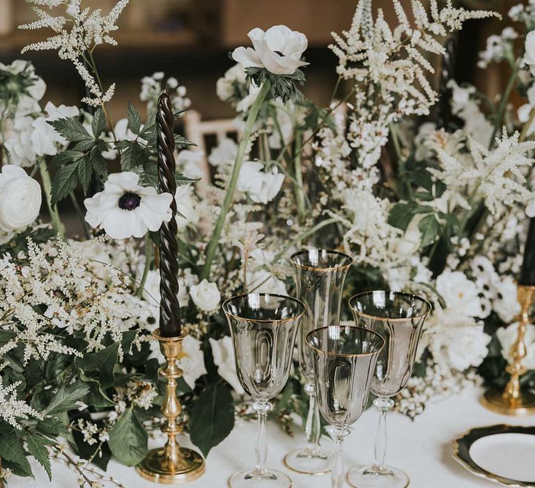 Elegant wedding tableware with black, white and gold plates, gold cutlery and smokey glassware 