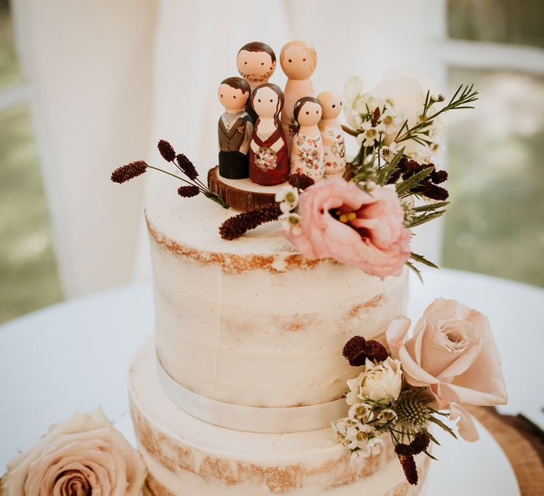 Wooden peg family wedding cake toppers on a semi naked wedding cake 