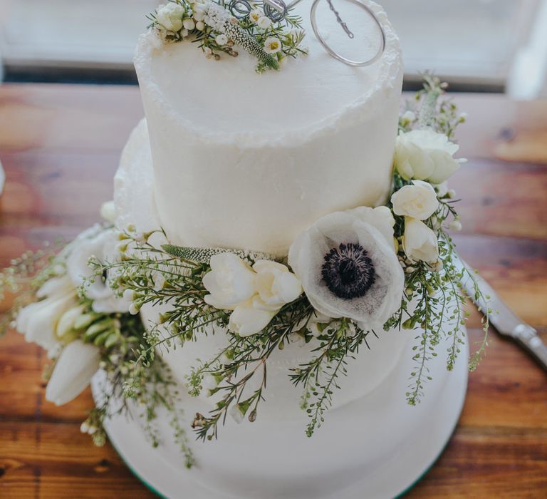 Homemade tandem bike cake topper on a two tier wedding cake decorated with white and green flowers 