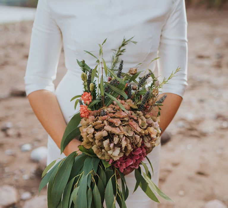 Bride carries Autumnal bouquet complete with green foliage