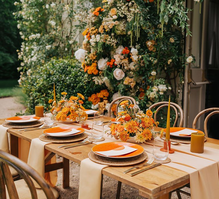 Outdoor wedding table decor with natural furniture, orange flowers and tableware 