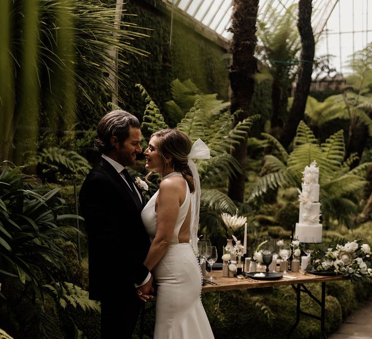 Bride in a Martina Liana halterneck wedding dress with puddle train, buttons and bow hair accessory 