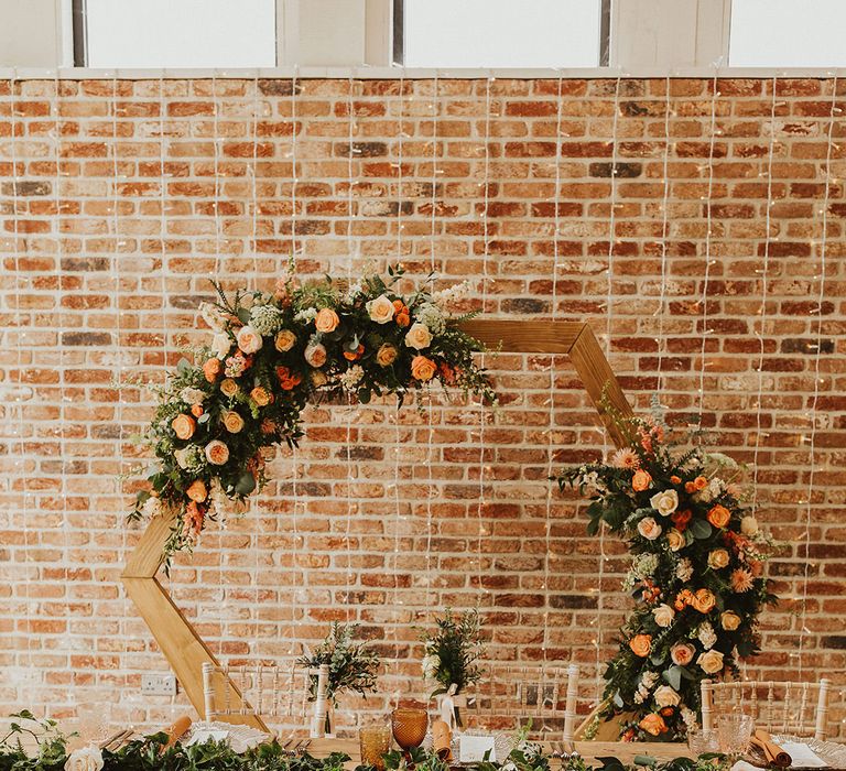 Hexagon wedding decor with orange flowers for backdrop to couples dinner