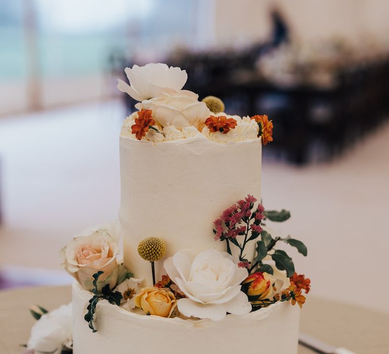 Two tier white wedding cake with floral decor for rustic wedding reception