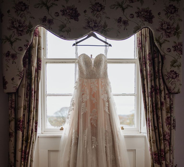 Stunning wedding dress hangs in front of window in Horetown House