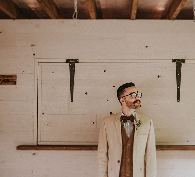 Groom wears sandy blazer complete with brown waistcoat and floral buttonhole 