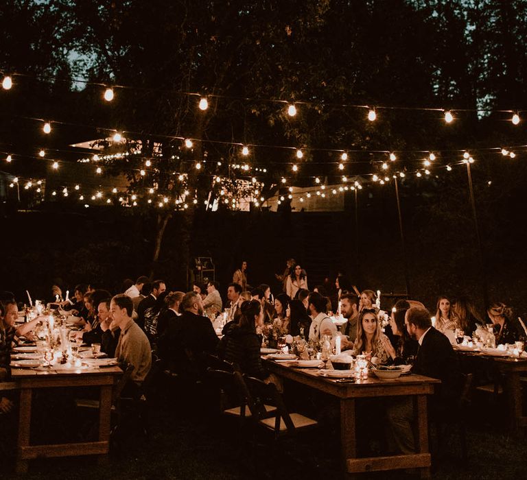 Guests gather outdoors for reception surrounded by candlelight 