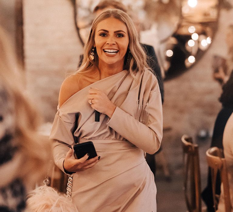 Wedding guest in a beige one shoulder satin dress 