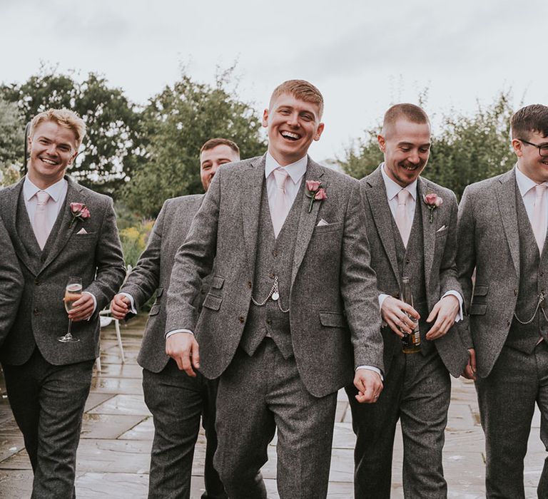 All of the groomsman together in matching grey tweed suits with pink ties and pink rose buttonholes