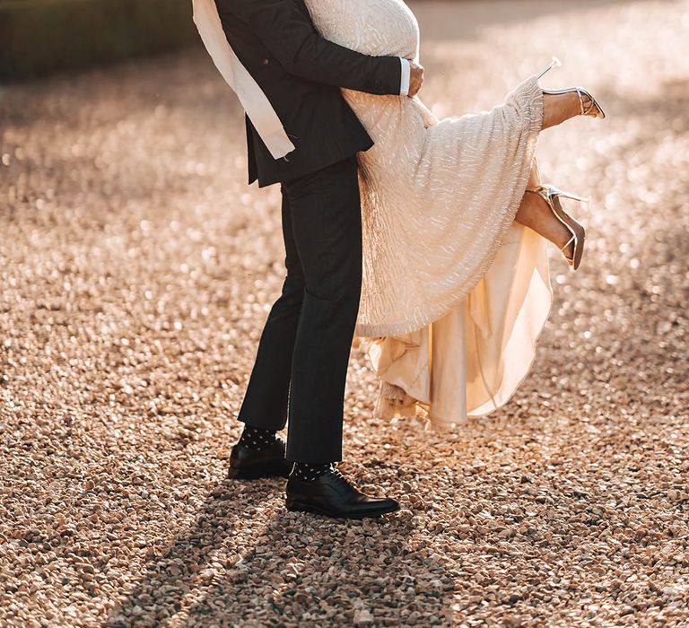 Groom lifts up bride in beaded wedding dress and kisses her after wedding at Pennard House