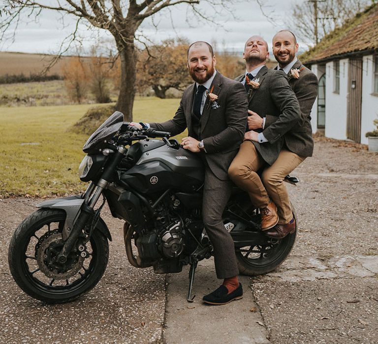 Groom poses with groomsmen on a motorbike