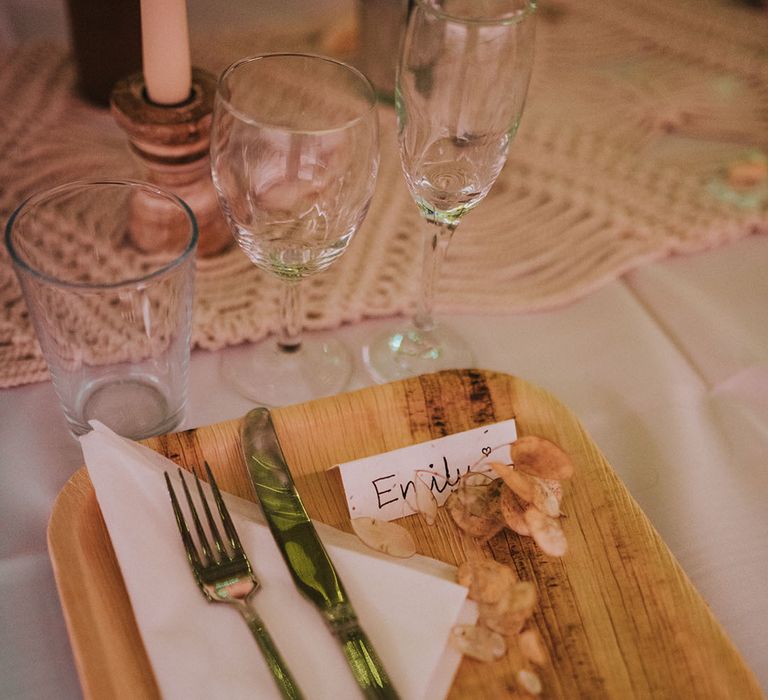 Wooden place setting for wedding guests with gold cutlery and hand written name card