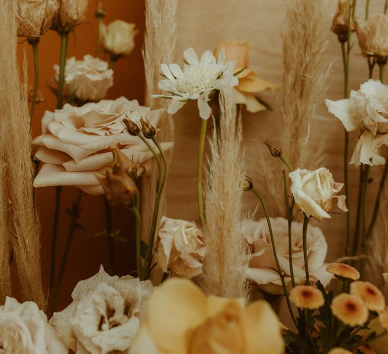 Neutral wedding flowers with dried grass decorate the couple's barn wedding 