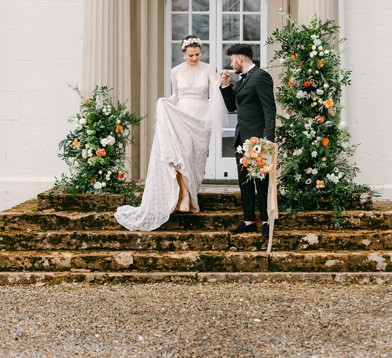 Black tie wedding with groom in a tuxedo and bride in an embellished wedding dress walking down the steps at Holesfoot wedding venue in Cumbria 